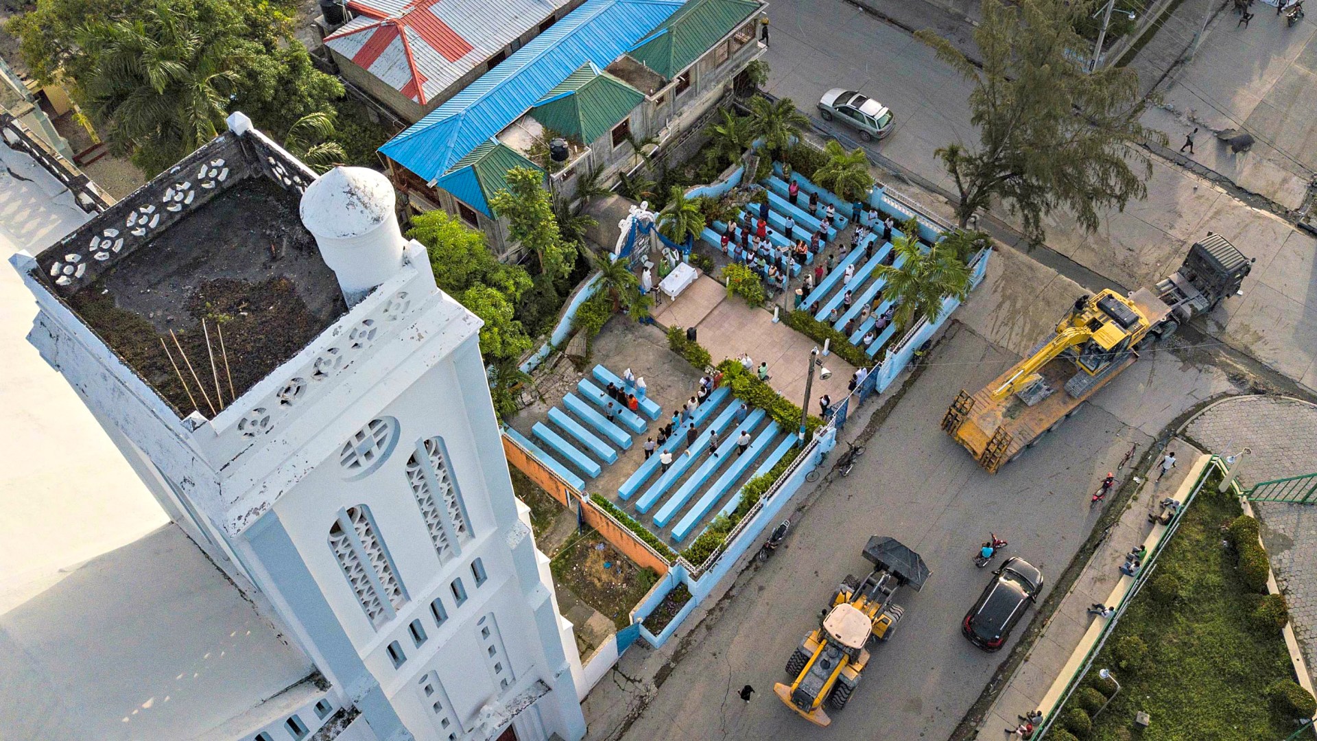 Des paroissiens assistent à une messe sur le terrain jouxtant une cathédrale endommagée par le tremblement de terre aux Cayes, à Haïti, le dimanche 22 août 2021, huit jours après le séisme de magnitude 7,2 qui a frappé la région.