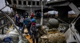 Des personnes évacuées traversent un pont détruit pour fuir la ville d’Irpin, au nord-ouest de Kiev, le 7 mars 2022.