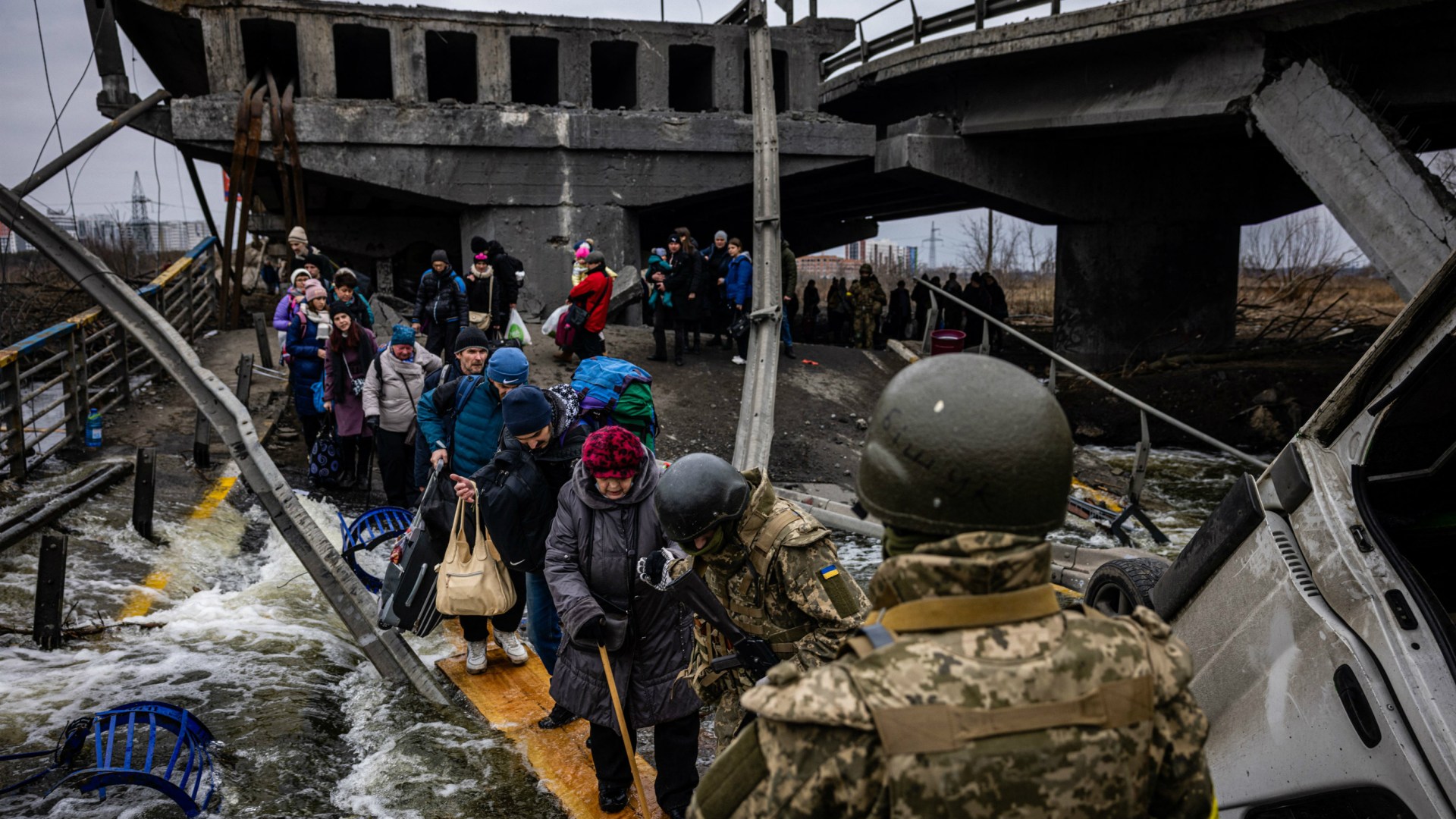 Des personnes évacuées traversent un pont détruit pour fuir la ville d’Irpin, au nord-ouest de Kiev, le 7 mars 2022.