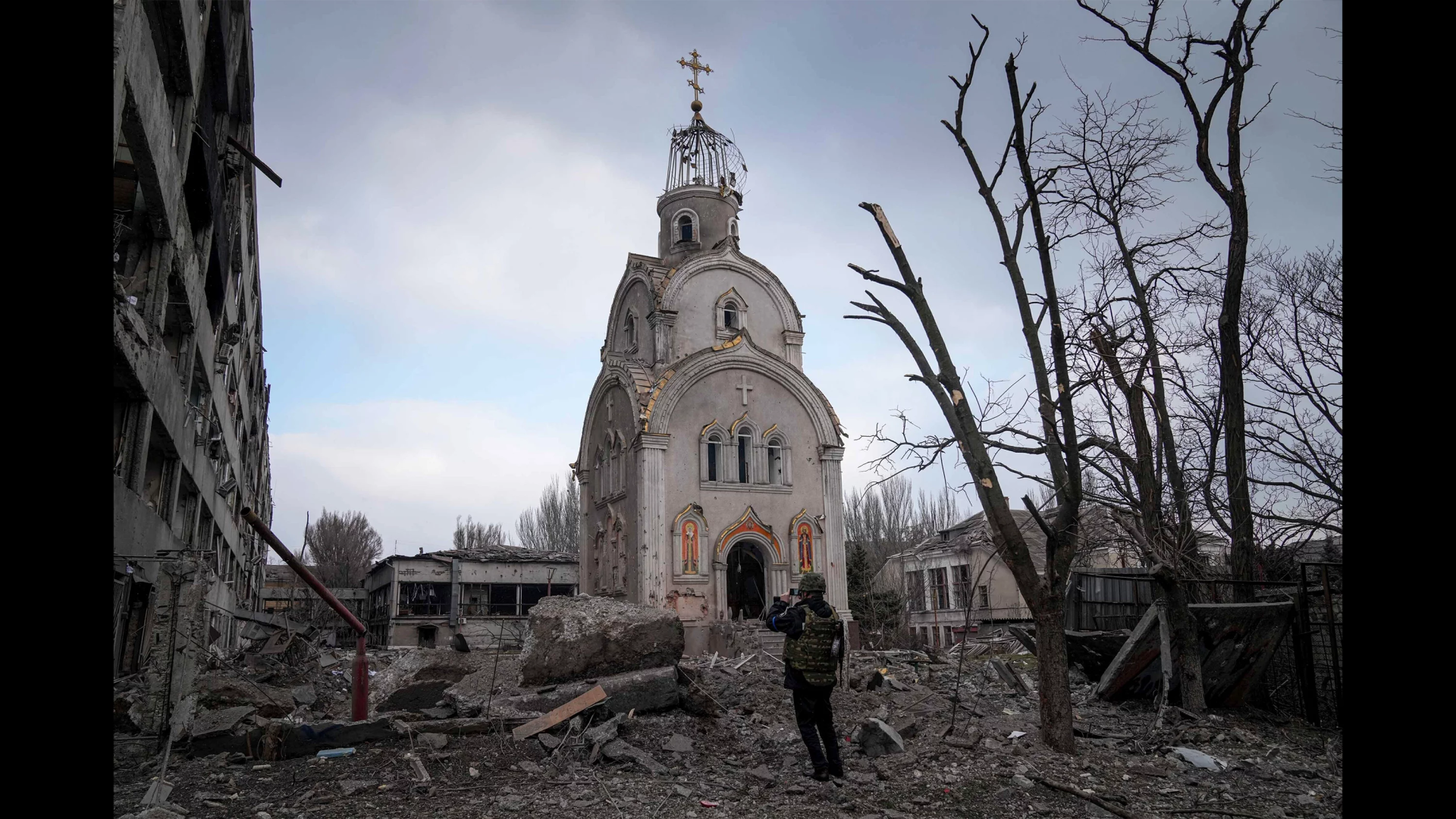 Un soldat ukrainien photographie une église endommagée après un bombardement dans un quartier résidentiel de Marioupol, en Ukraine, le 10 mars 2022.