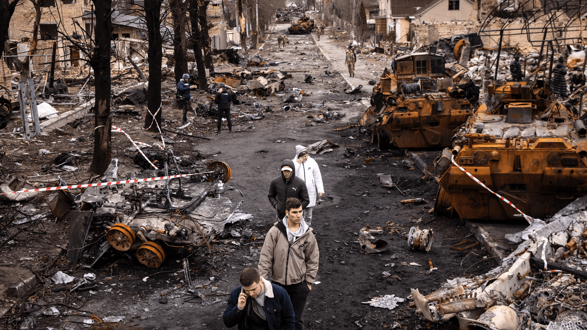 Des gens circulent au milieu de débris et de véhicules militaires russes détruits dans une rue de Boutcha, en Ukraine, le 6 avril 2022.