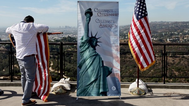 A man furls a flag after a US naturalization ceremony in Los Angeles for immigrants becoming citizens.