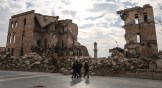 Syrians walk past one of Aleppo's destroyed structures near the northern city's historic citadel.