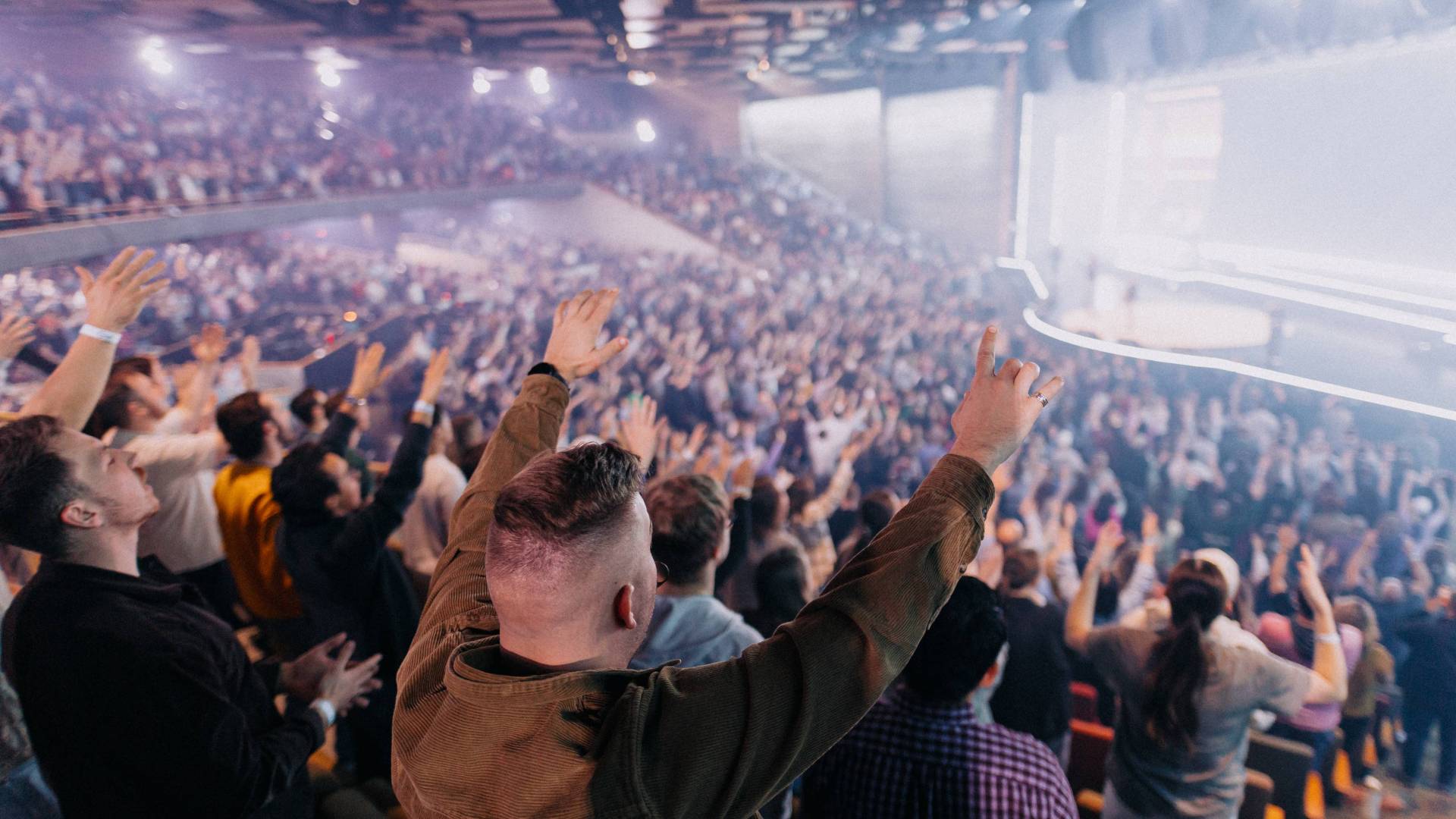 Arena filled with people raised hands in worship