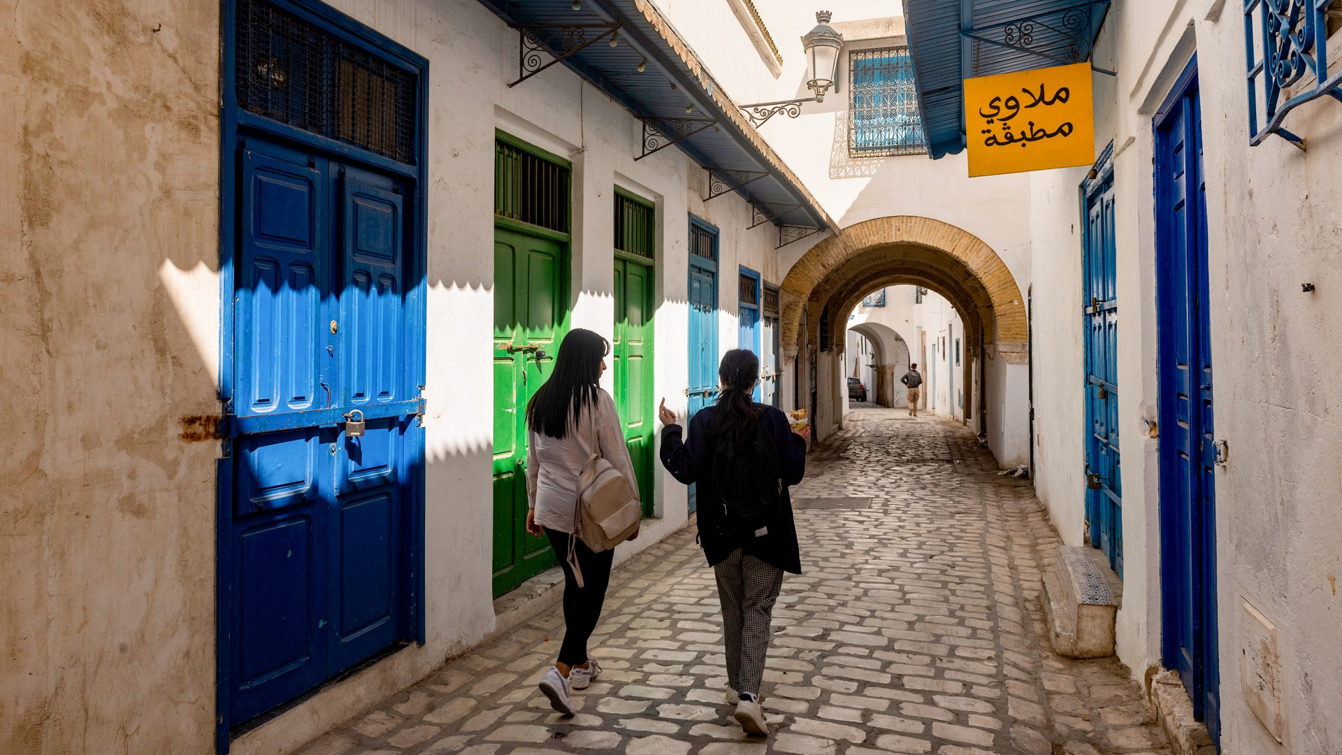 Two young Tunisian women walk in the traditionally decorated narrow streets of Tunis.