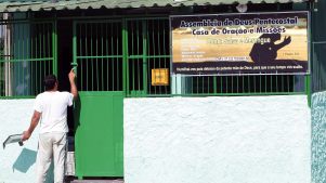 Man paints a gate of an Assemblies of God church in Brazil