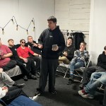 Pastor Alex Zaytsev, on the end of the couch in a red shirt, hosting his teen ministry.