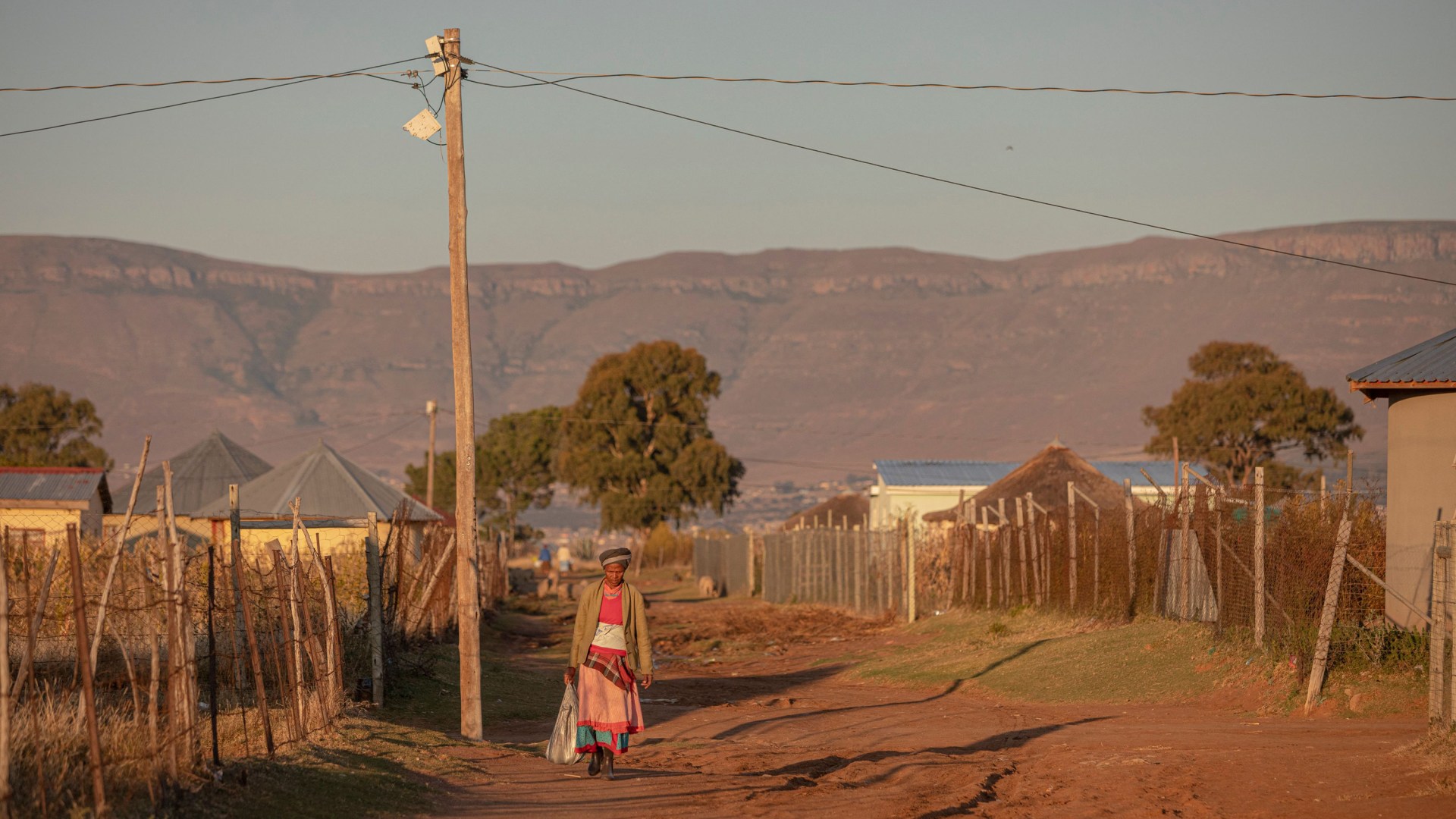 Une femme marchant sur un chemin de terre dans le village de Zingqolweni, en Afrique du Sud.